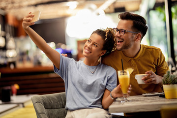 Cheerful couple having fun and taking selfie in a bar.