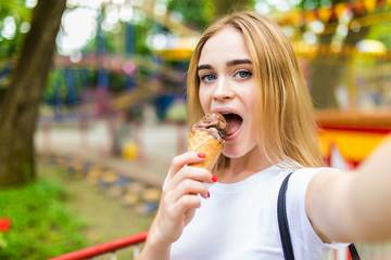 Pretty cheerful young woman walking in park with ice cream