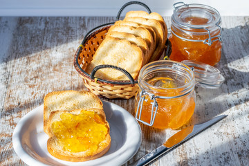Fried toasts and homemade orange jam on the wooden rustic table.