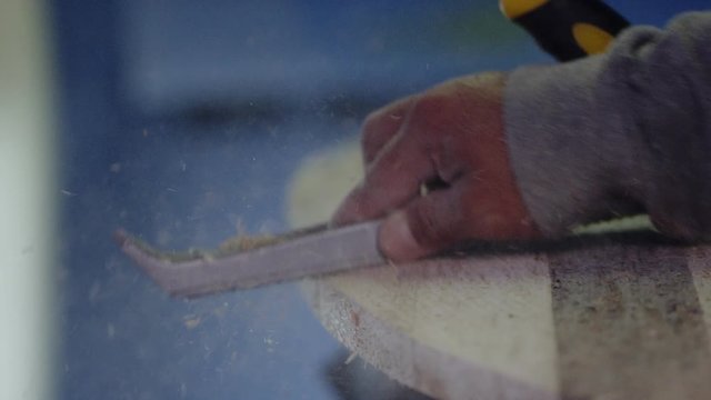 Craftsperson uses a rasp to shape a surfboard