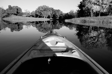 Kayak boat on water in black and white, calm rural view.