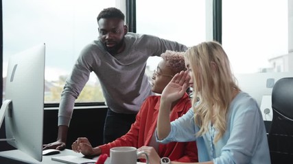 Team of ambitious multi-race office people working by desktop computer managing business financial deals together. Modern office. Excellent teamwork.