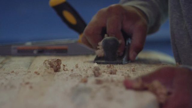 Craftsperson uses a planer to shape a surfboard