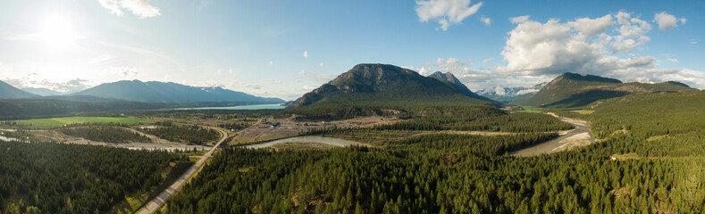 Fototapeta premium Aerial Panoramic View of Small Town, Canal Flats, during a sunny and cloudy summer day. Located in the Kootenay, British Columbia, Canada.