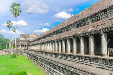 Fototapeta na wymiar Ancient Angkor Wat temple and palm trees under summer cloud blue sky