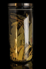 closeup aromatic dried bay leaves in tall glass jar with metal cap