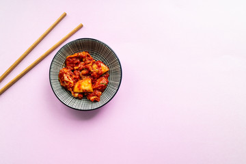 Korean spicy kimchi with chopsticks on pink background. Top view. - obrazy, fototapety, plakaty