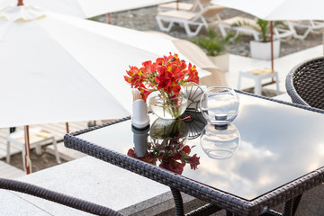 Beautiful flowers on a glass table of a seaside outdoor restaurant