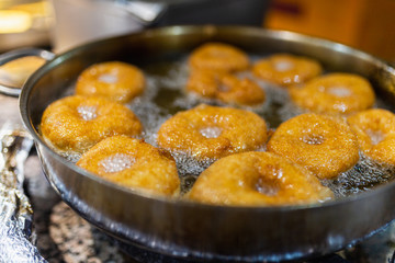 The dough is cooked in hot boiling oil. Donuts fry in a pan with hot oil