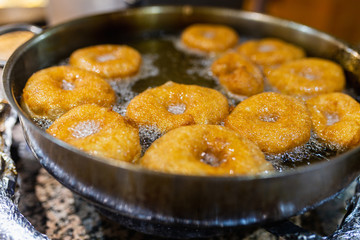 The dough is cooked in hot boiling oil. Donuts fry in a pan with hot oil