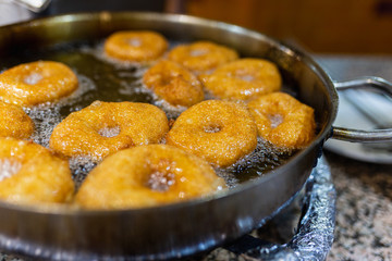 The dough is cooked in hot boiling oil. Donuts fry in a pan with hot oil