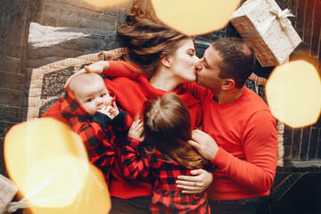 Beautiful mother in a red dress. Family lying near christmas gifts. Little girl and boy near christmas tree