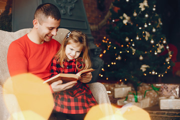 Father in a red sweater. Family sitting near christmas gifts. Little girl near christmas tree