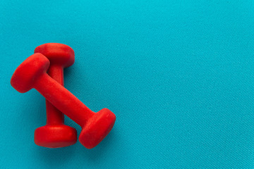 Red dumbbells on a blue fitness mat