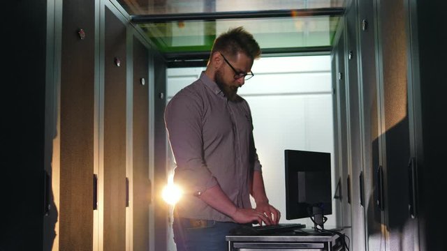 Male programmer works with computer in server room.