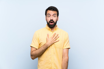Naklejka premium Young man with beard over isolated blue background surprised and shocked while looking right