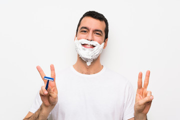 Man shaving his beard over isolated white background showing victory sign with both hands