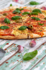 Freshly made wood fired pizza viewed from above on rustic turquoise boards