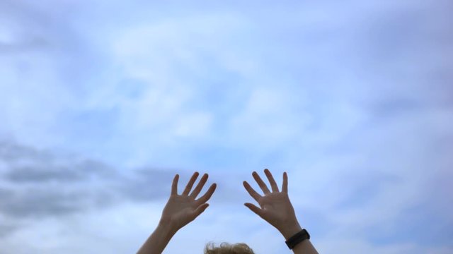 Man hands being put up in the air on blue cloudy sky background, freedom concept. Art. Man with a watch on his wrist and his hand in the air.