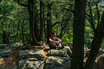 Fototapeta premium A young caucasian male hiker sitting the woods enjoying the outdoors.