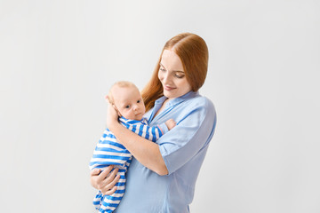 Mother with cute baby on light background