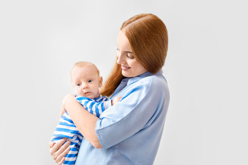Mother with cute baby on light background