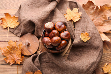 Beautiful autumn composition with chestnuts and leaves on wooden background