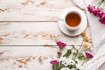 Autumn composition with cup of tea and flowers on white wooden background
