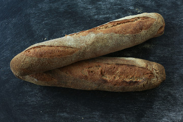 Baguette . Fresh homemade bread. long rectangular bread baguette on a dark background. Mother dough bread. Loaves of bread lie in rows