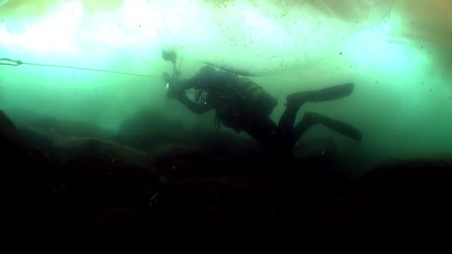 Underwater video shooting under ice in cold water of people on ice surface as concept of winter wild nature of lake Baikal.