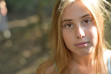 Naklejka premium Close up portrait of a girl in a natural environment in a white dress looking at the camera