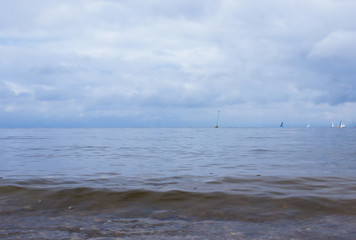 Horizon of the sea and sky with sails in the far.