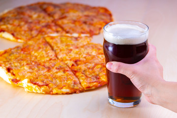 Close up of a person hold a red beer with pizza