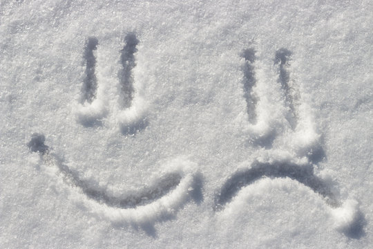 Sad and funny Smile emoji painted on the snow, close-up, top view