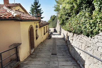 Fototapeta na wymiar Narrow paved street with old houses in the old district of the San Marino city
