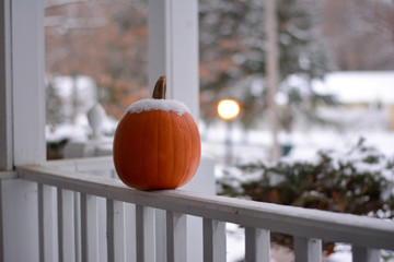 Snow on a pumpkin on a porch