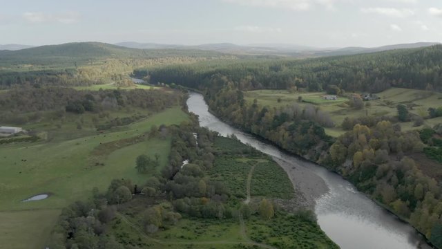 Aerial view of the River Dee near the Scottish town of Ballater in the Cairngorms National Park, Aberdeenshire. Flying forward over fields and the river with zoom in.