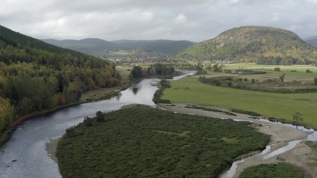 Aerial view of the River Dee near the Scottish town of Ballater in the Cairngorms National Park, Aberdeenshire. Flying forward over fields and the river with zoom in.