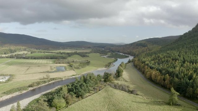 Aerial view of the River Dee near the Scottish town of Ballater in the Cairngorms National Park, Aberdeenshire. Flying forward over fields and the river with zoom in.