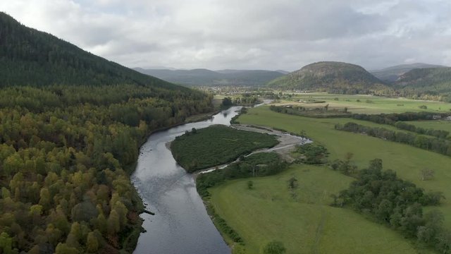 Aerial view of the River Dee near the Scottish town of Ballater in the Cairngorms National Park, Aberdeenshire. Flying forward over fields and the river.