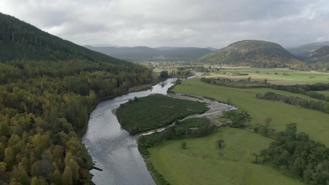 Aerial view of the River Dee near the Scottish town of Ballater in the Cairngorms National Park, Aberdeenshire. Flying forward over fields and the river with zoom in.