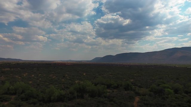Time-lapse of clouds moving over mountains & bush field. Shadows of clouds moving & revealing the sun and the beautiful nature underneath it.