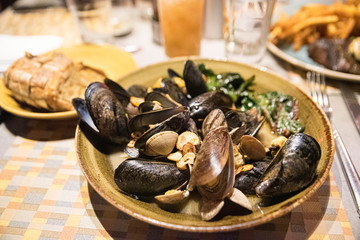 A plate of mussels and clams on a restaurant table in warm orange light