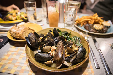 A plate of mussels and clams on a restaurant table in warm orange light
