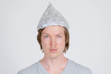 Face of young man with tinfoil hat as conspiracy theory concept