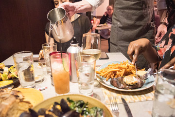 A waiter pouring water for customers at a restaurant in orange lighting