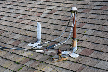 Suburban house rooftop, asphalt shingles, electrical power masthead, skylight with cover, roof vents