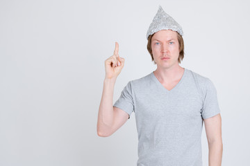 Young man with tinfoil hat as conspiracy theory concept pointing up