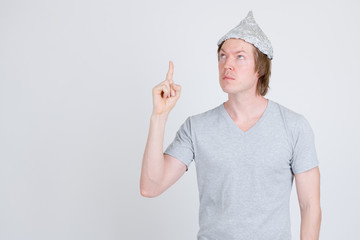 Young man with tinfoil hat as conspiracy theory concept pointing up