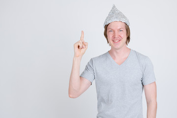 Happy young man with tinfoil hat as conspiracy theory concept pointing up